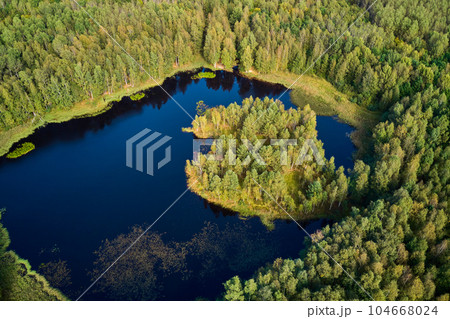 Aerial view of a picturesque landscape with a peat lake and a small island surrounded by green forest 104668024