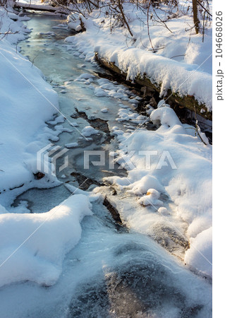 Ice-covered frozen stream in winter, vertical view 104668026