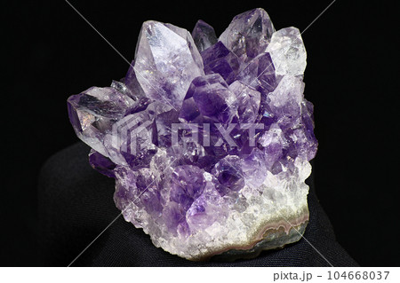 Amethyst druse on a dark background close up. Cluster of lilac crystals Amethyst druse on a dark background close up. Cluster of lilac crystals 104668037