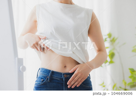 鏡でお腹をチェックする女性 104669006