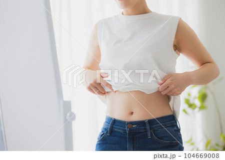 鏡でお腹をチェックする女性 鏡でお腹をチェックする女性 104669008