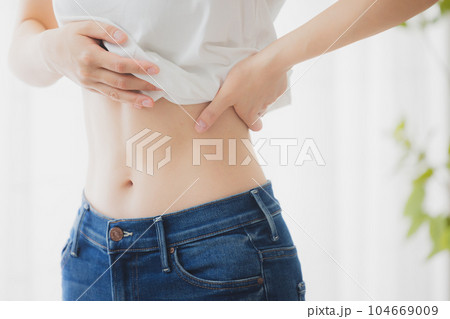 鏡でお腹をチェックする女性 104669009