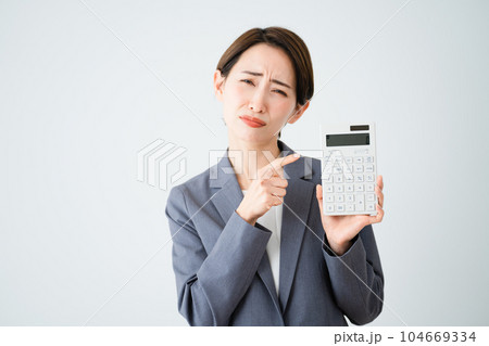 電卓を持って指をさす若い女性 ビジネスイメージ 電卓を持って指をさす若い女性 ビジネスイメージ 104669334