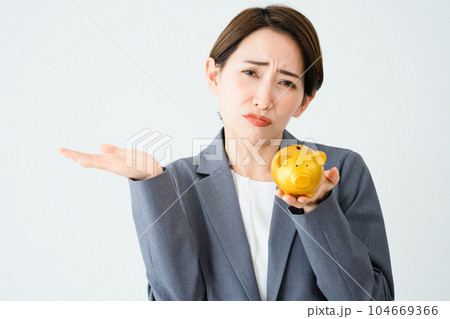 豚の貯金箱を持って肩をすくめる若い女性　ビジネスイメージ 104669366