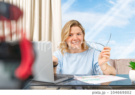 Middle aged woman making financial, investment or saving money content. Blogger creating content Middle aged woman making financial, investment or saving money content. Blogger creating content 104669802