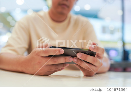 Man playing game on mobile phone. gamer boy playing video games holding Smartphone working mobile devices. cell telephone technology e-commerce concept Man playing game on mobile phone. gamer boy playing video games holding Smartphone working mobile devices. cell telephone technology e-commerce concept 104671364