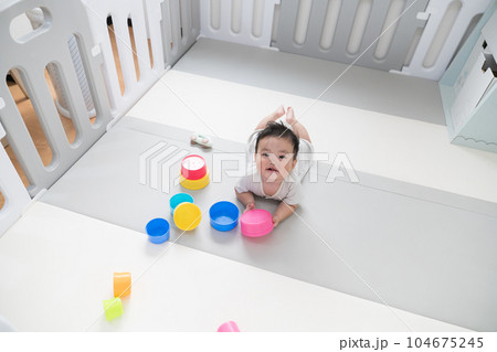 自然光が入るリビングのプレイマットで知育おもちゃを使って遊ぶご機嫌な生後8か月の赤ちゃん 自然光が入るリビングのプレイマットで知育おもちゃを使って遊ぶご機嫌な生後8か月の赤ちゃん 104675245
