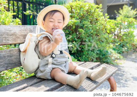 ベンチに座って水分補給する笑う赤ちゃん 104675692