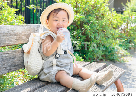 ベンチに座って水分補給する赤ちゃん 104675693