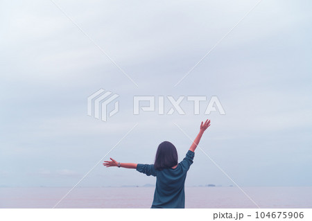 Young woman rise hand up to sky feel relax and free with summer beach background. Young woman rise hand up to sky feel relax and free with summer beach background. 104675906