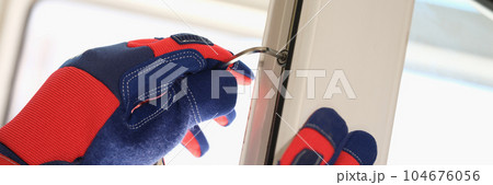 Male worker in protective gloves adjusting lock of pvc windows with special key 104676056