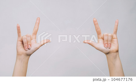 Rock sign. Punk gesture. Woman fingers showing horns symbols isolated on gray free space background. 104677176