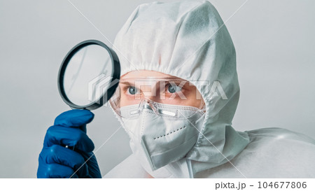 Virology research. Medical examination. Woman doctor laboratory specialist in white protective suit equipment with loupe isolated on grey background. 104677806