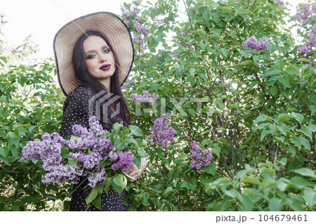 A fashionable girl with dark hair, a spring portrait in lilac tones in summer. Bright professional makeup. A fashionable girl with dark hair, a spring portrait in lilac tones in summer. Bright professional makeup. 104679461