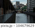 都会の川と夕暮れに染まりだすビル群 104679629