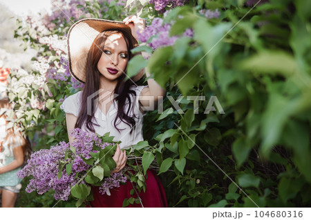 A fashionable girl with dark hair, a spring portrait in lilac tones in summer. Bright professional makeup. 104680316