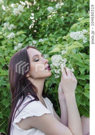 A fashionable girl with dark hair, a spring portrait in lilac tones in summer. Bright professional makeup. A fashionable girl with dark hair, a spring portrait in lilac tones in summer. Bright professional makeup. 104680319
