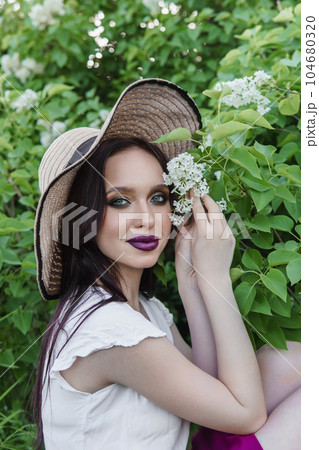 A fashionable girl with dark hair, a spring portrait in lilac tones in summer. Bright professional makeup. A fashionable girl with dark hair, a spring portrait in lilac tones in summer. Bright professional makeup. 104680320