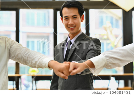 Group of businesspeople making a fist bump, excited after completion of project, celebrate their unity in the office Group of businesspeople making a fist bump, excited after completion of project, celebrate their unity in the office 104681451