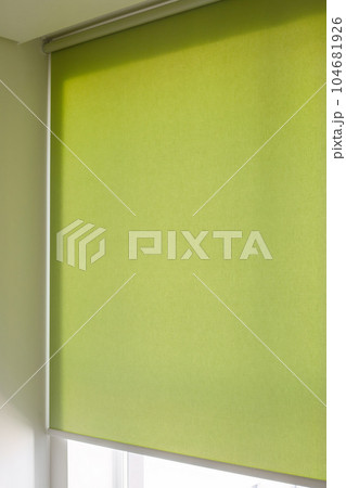 Roller blinds automatic close-up on the window. Selective focus. Motorized shades. Green color curtain, texture fabric. City outside the window. 104681926