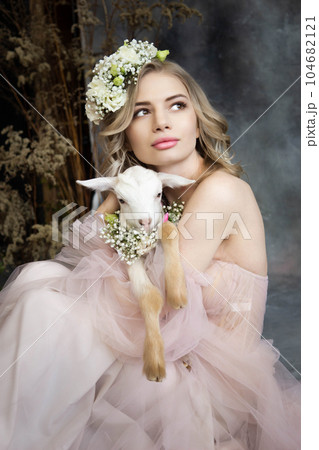 A young blonde woman in an airy pink dress with a white kid. Spring portrait of a woman. A young blonde woman in an airy pink dress with a white kid. Spring portrait of a woman. 104682121