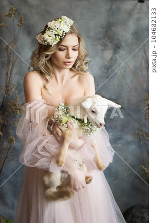 A young blonde woman in an airy pink dress with a white kid. Spring portrait of a woman. 104682133