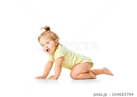 Cheerful, joyful, happy little baby, girl, toddler crawling and laughing against white studio background. Curious child 104683764