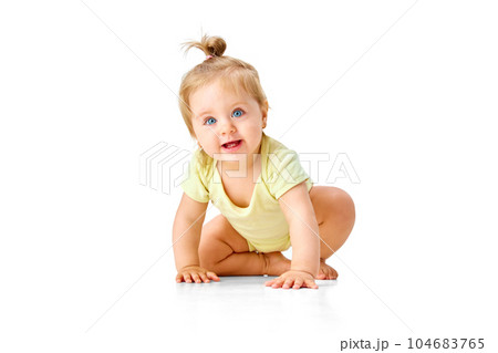 Curious little baby girl, toddler crawling forward and attentively looking with interest against white studio background 104683765