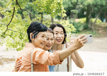 友達とスマホで写真を撮るミドル女性 友達とスマホで写真を撮るミドル女性 104686027
