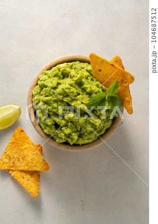 Guacamole avocado mash dip, with tortilla chips and fresh avocados 104687512