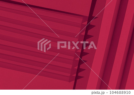 Viva Magenta color of the year 2023. Abstract crimson red color  paper texture. Folded paper with harsh sun shadows, geometric shapes and lines. 104688910