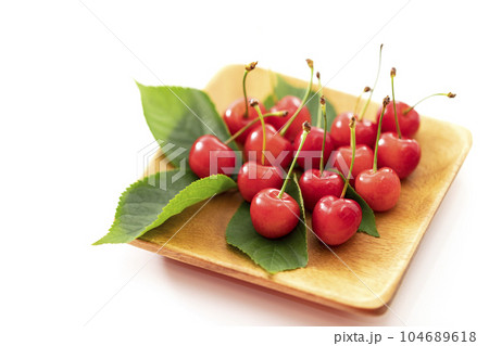白バックで木の角皿に乗せ葉を添えた初夏の果物さくらんぼ 104689618