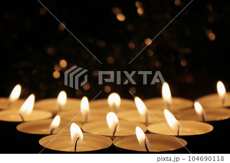 White Candles Burning in the Dark with focus on two candles in foreground. 104690118