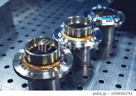 New freshly welded stainless steel flanges. Demonstration of reference multi-colored seams 104690242