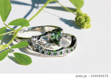 Claddagh ring with green emerald. Traditional Irish ring in shape of two hands holding a heart shaped green gemstone. Symbol of love, loyalty and friendship. Claddagh ring with green emerald. Traditional Irish ring in shape of two hands holding a heart shaped green gemstone. Symbol of love, loyalty and friendship. 104690878