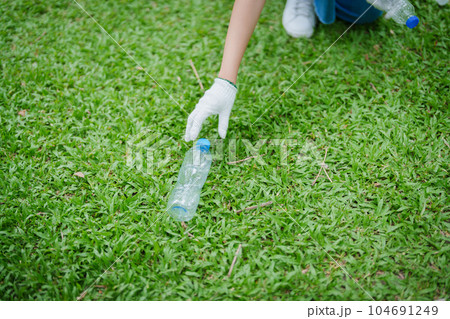 Multiethnic volunteers donate their time holding black garbage bags to collect plastic waste for recycling to reduce pollution in a public park 104691249