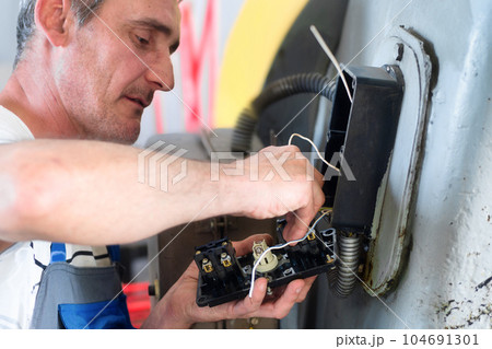 Professional electrician repairs industrial equipment in production workshop. Diagnostics of power Professional electrician repairs industrial equipment in production workshop. Diagnostics of power 104691301