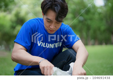 Multiethnic volunteers donate their time holding black garbage bags to collect plastic waste for recycling to reduce pollution in a public park 104691438