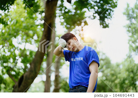 Multiethnic volunteers donate their time holding black garbage bags to collect plastic waste for recycling to reduce pollution in a public park 104691443