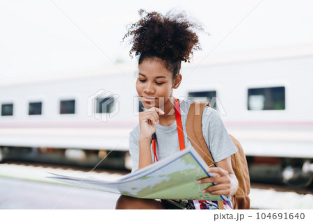 Asian teenage girl african american traveler dressed in casual wear holding map and searching right direction of route Asian teenage girl african american traveler dressed in casual wear holding map and searching right direction of route 104691640