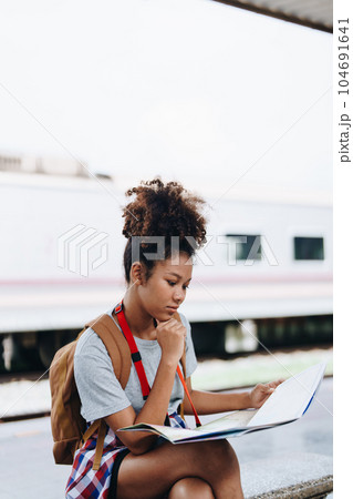 Asian teenage girl african american traveler dressed in casual wear holding map and searching right direction of route 104691641