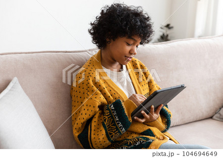 African american girl holding digital tablet touch screen typing scroll page at home. Woman with mobile tech device surfing internet using social media apps playing game. Study work shopping online African american girl holding digital tablet touch screen typing scroll page at home. Woman with mobile tech device surfing internet using social media apps playing game. Study work shopping online 104694649