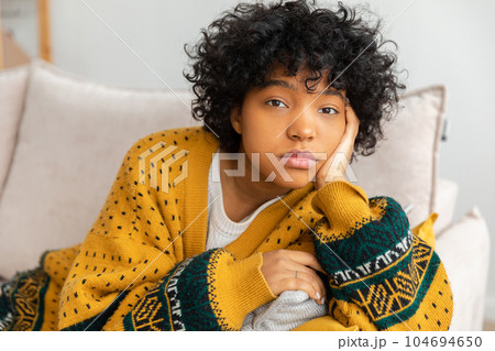 African american sad thoughtful pensive unmotivated girl sitting on sofa at home indoor. Young african woman ponder look tired after long day. Girl feels depressed offended lonely upset heartbreak 104694650