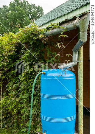 water collection tank under a roof with a drain. Rain water harvesting 104694771