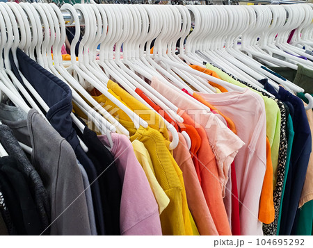 Old clothes are hung on hangers in a second-hand store. 104695292