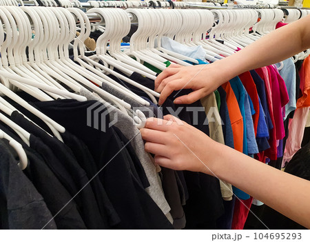 Women's hands are sorting through clothes on hangers Women's hands are sorting through clothes on hangers 104695293