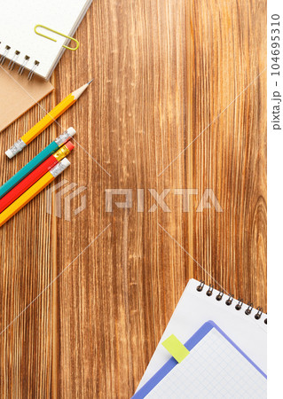 Notepad with school supplies on a wooden desk. 104695310