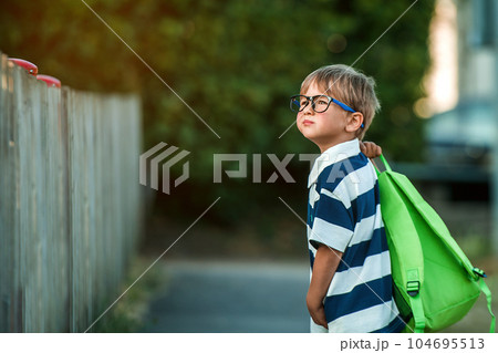 Back to school. A boy from an elementary school with a backpack on the street. The concept of the day of knowledge, The beginning of school. Smart little child in glasses Back to school. A boy from an elementary school with a backpack on the street. The concept of the day of knowledge, The beginning of school. Smart little child in glasses 104695513