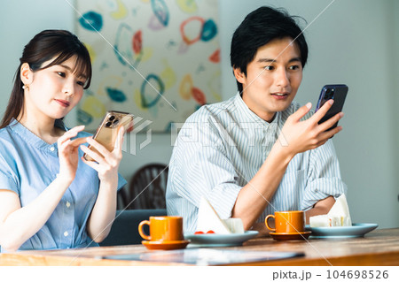 デート中スマホに集中するカップル 104698526