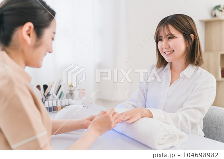 ネイルサロンでベースコートを塗るネイリストと女性 ネイルサロンでベースコートを塗るネイリストと女性 104698982